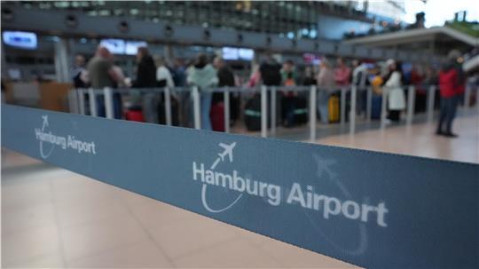 Flugpassagiere stehen an den Check-in-Schaltern in der Abflughalle des Hamburg Airports Schlange. 