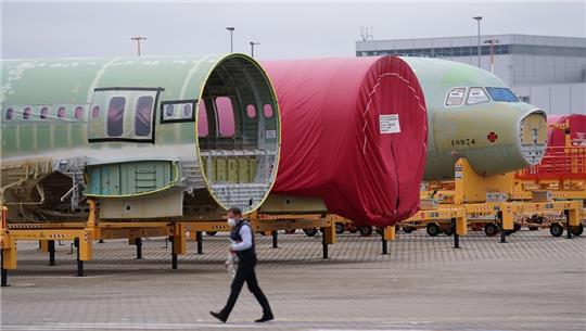 Flugzeugsegmente stehen vor einer Montagehalle für A321-Flugzeuge im Airbus-Werk in Hamburg-Finkenwerder. Foto: Marcus Brandt/dpa