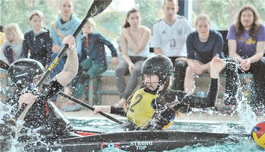 Foto aus der Wasserperspektive: Tobias Harzer von Buxtehude 2 (vorne) beobachtet, wie der gegnerische Spieler mit seinem Paddel einen Torwurf blocken will.