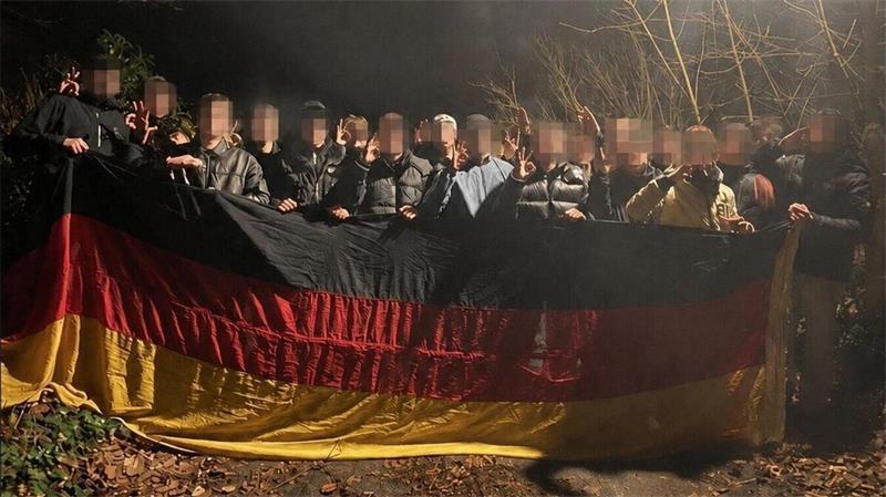 Foto mit politischer Brisanz: Auf der rund zwei Jahre alten Aufnahme posieren mehrere junge Männer, darunter ein Kandidat für den Cuxhavener Stadtrat, nachts im Wald mit Deutschlandflagge und umstrittenen Handzeichen. 