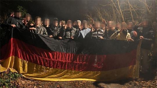 Foto mit politischer Brisanz: Auf der rund zwei Jahre alten Aufnahme posieren mehrere junge Männer, darunter ein Kandidat für den Cuxhavener Stadtrat, nachts im Wald mit Deutschlandflagge und umstrittenen Handzeichen. 