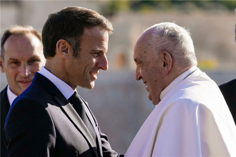 Frankreichs Präsident Emmanuel Macron (l) begrüßt Papst Franziskus.