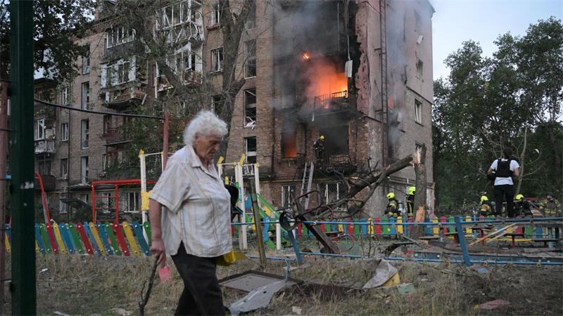Frau passiert brennendes Wohnhaus nach russischem Angriff in Kiew
