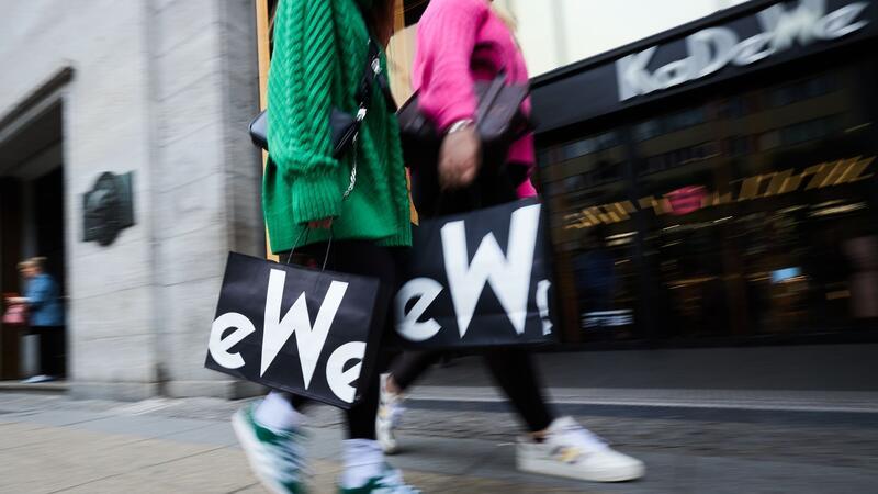 Frauen mit KaDeWe-Tragetaschen gehen am Eingang des Kaufhauses des Westens vorbei.