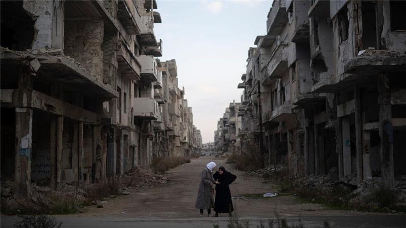 Frauen unterhalten sich auf einer Straße inmitten von Kriegsruinen.
