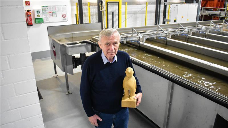 Gerhard Umlandt mit einer Holzskulptur unter seinem linken Arm in der Halle seines Obsthandel-Familienbetriebs.