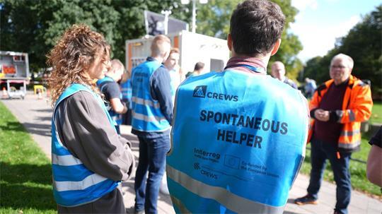 Freiwillige und spontane Helferinnen und Helfer besprechen sich an der Sammelstelle am Altona Balkon während der Einsatzübung zum EU-Projekt Crews.  