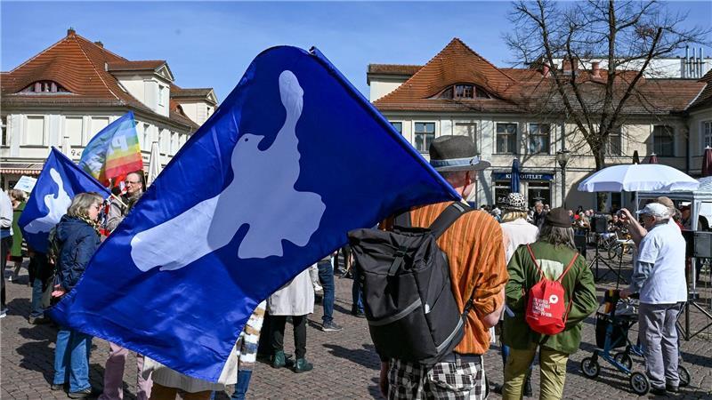 Friedenstauben sind auf Fahnen bei einem Ostermarsch zu sehen.