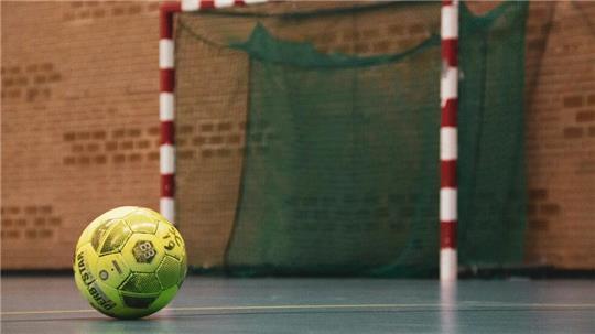 Ein Fußball liegt in der Halle vor einem Tor.
