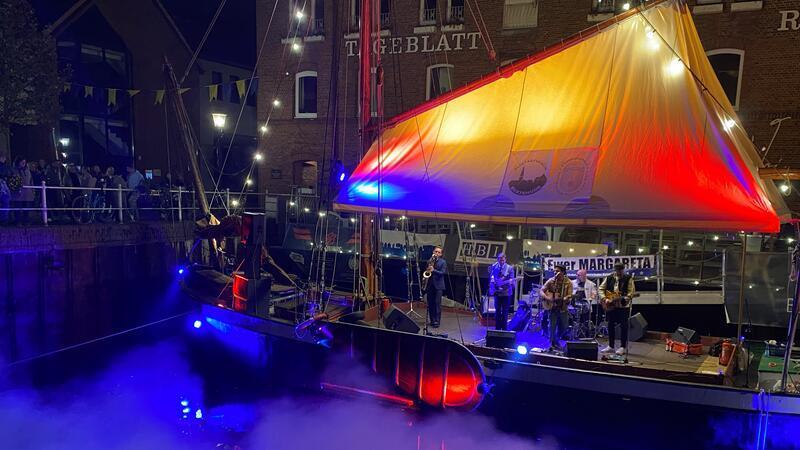 Eine Band rockt die bunt beleuchtete Bühne an Deck vom Ewer Margareta 