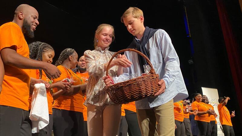 Conrad Ramdohr und Theresa Braun gehen mit einem Korb voller Marmeladengläser die Reihe der Musiker ab
