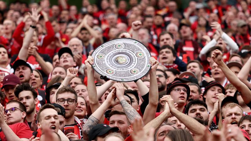 Fußball: Ein Leverkusener Fan hält während des Spiels eine Nachbildung der Meisterschale in den Händen. Bayer Leverkusen gewinnt die Deutsche Meisterschaft.