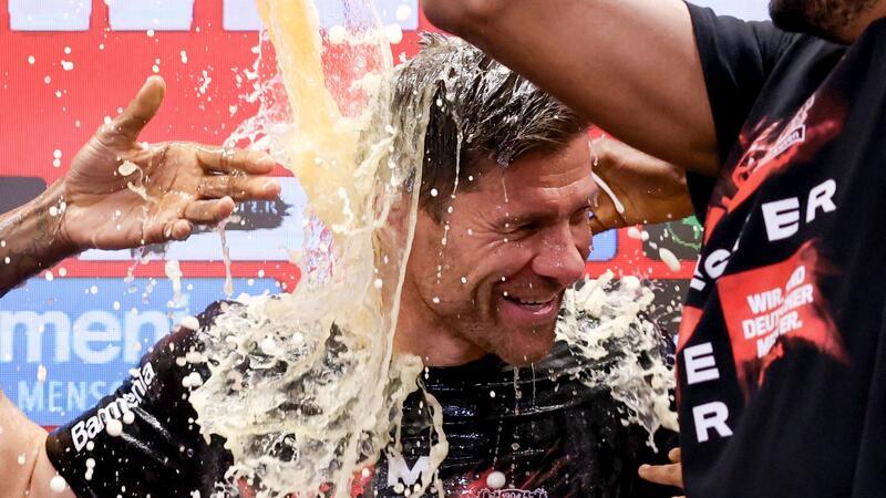 Alonso nach Meisterschaft erfolgshungrig: „Wir wollen mehr“ Fußball: Leverkusens Trainer Xabi Alonso wird bei der Pressekonferenz nach dem Spiel von seinen Spielern mit Bier übergossen. Leverkusen gewinnt die Deutsche Meisterschaft.