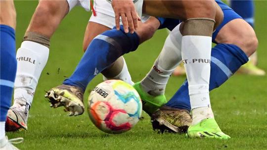 Fußballspieler zweier gegnerischer Mannschaften kämpfen um den Ball.