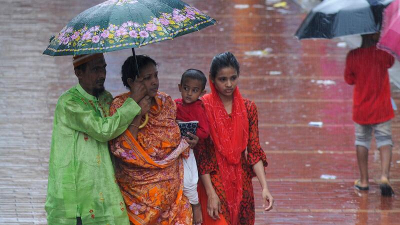 Fußgängerinnen gehen in Bangladesh durch den Regen.