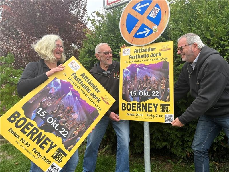 Gabi Frieß, Herbert Scharf und Frank Deppe von „Lust auf Kultur“ hängen Plakate für die Jubiläumsparty mit Boerney und die Tri Tops in der Altländer Festhalle in Jork auf (von links). Foto: Vasel