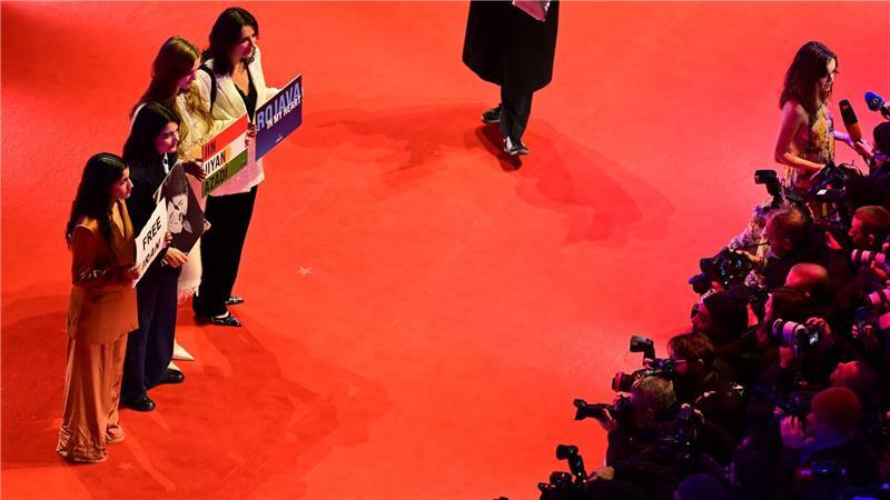 Gäste, darunter die deutsch-iranische Schauspielerin Jasmin Tabatabai (2. v. l.), halten Protestschilder hoch.