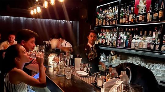 Gäste sitzen am Tresen einer Bar in Bangkok.