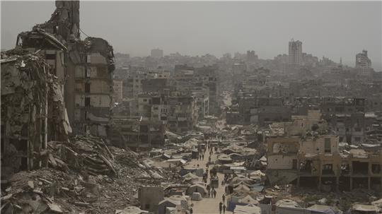 Gaza-Stadt: Menschen gehen eine Straße entlang, die von Gebäuden umgeben ist, die durch israelische Bombardierungen im Gazastreifen zerstört wurden (Archivbild).