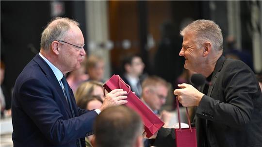 Geburtstagsgruß im Parlament: SPD-Fraktionschef Politze (r) überreicht Ex-Ministerpräsident Weil (l) eine Flasche Wein.