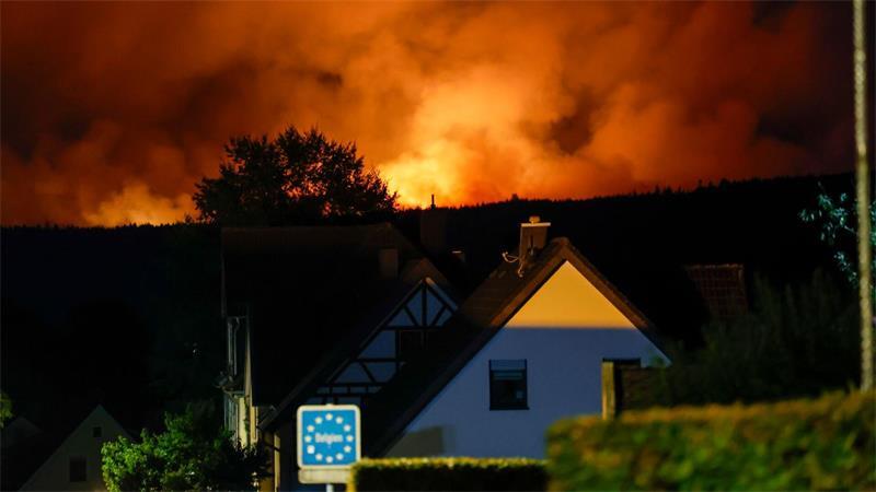 Gefährlich nah: Die Flammen des Brandes im Hohen Venn sind schon hinter einem Haus in Monschau zu sehen. 