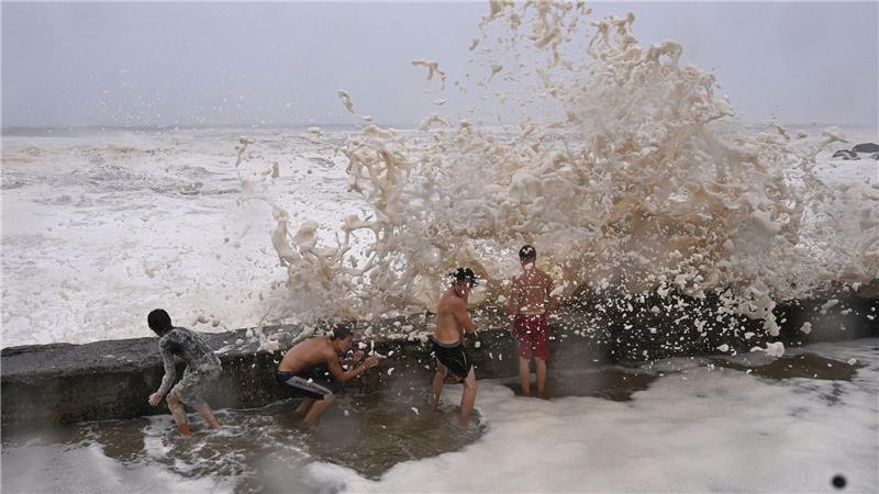 Gefährliche Wellen: Jungen schützen sich an der Goldküste vor den Wellen des Wirbelsturms „Alfred“ hinter einer Uferbefestigung. 