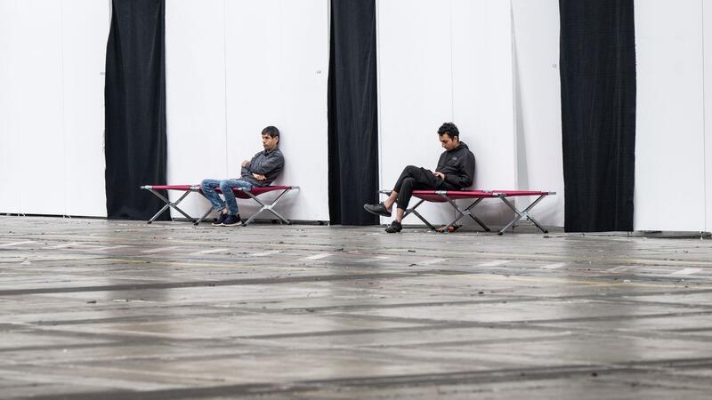 Integration: Asylbewerber und Flüchtlinge wollen mehr Hilfe Geflüchtete sitzen auf Feldbetten in einer Massenunterkunft in Frankfurt: Viele Geflüchtete wünschen sich mehr Hilfe in Asyl- und Flüchtlingsfragen.