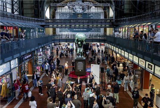Geladene Gäste betrachten die enthüllte Atlas-Skulptur im Hauptbahnhof. Die Atlas-Skulptur, die einst auf dem Dach des Bahnhofs thronte, wird bis zum Herbst in der Wandelhalle ausgestellt. Foto: Axel Heimken/dpa