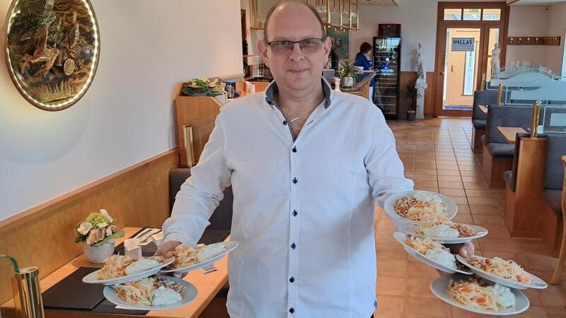 Warum Gäste zwei Stunden fahren, um in diesem Restaurant zu essen Gelernt ist gelernt: Georgios Stavrakoudis balanciert in seinem neuen griechischen Restaurant „Hellas“ in Lunestedt acht Teller mit Bohnen- und Krautsalat sowie Tzatziki.Foto: Jan Iven