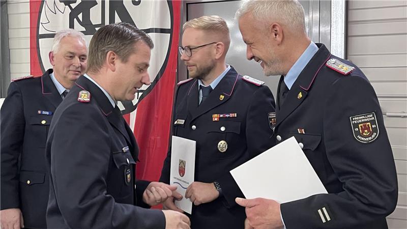 Gemeindebrandmeister Torben Schulze befördert seinen Stellvertreter Niels Bründel (rechts) und den Horneburger Ortsbrandmeister Dennis Dalchau (2. von rechts); links schaut der stellvertretende Kreisbrandmeister Thorsten Hellwege zu.