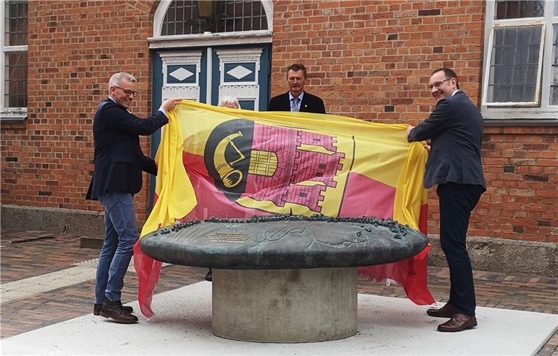 Gemeindedirektor Knut Willenbockel (links) und Matthias Lühmann, Vorsitzender der Kreissparkasse Stade, sowie Bürgermeister Jörk Philippsen (hinten) enthüllten das Relief. Foto: Samtgemeinde Horneburg/Kiefaber
