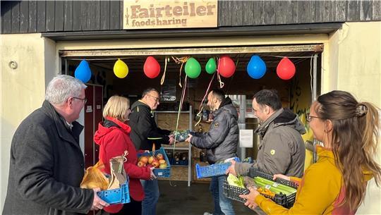 Gemeinsam werden die Regale und der Kühlschrank des Fairteilers am Jugendzentrum Woodstock bei der Einweihung im März 2025 gefüllt.