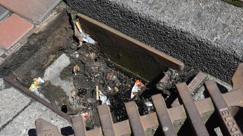 Geöffneter Gullydeckel an der Straße Am Geesttor unmittelbar an der Buxtehuder Altstadt: Zigarettenstummel und Verpackungen von Süßigkeiten landen darin.