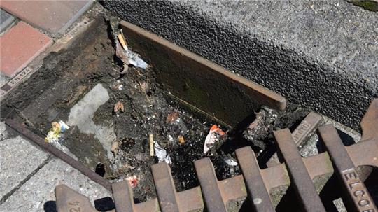 Geöffneter Gullydeckel an der Straße Am Geesttor unmittelbar an der Buxtehuder Altstadt: Zigarettenstummel und Verpackungen von Süßigkeiten landen darin.