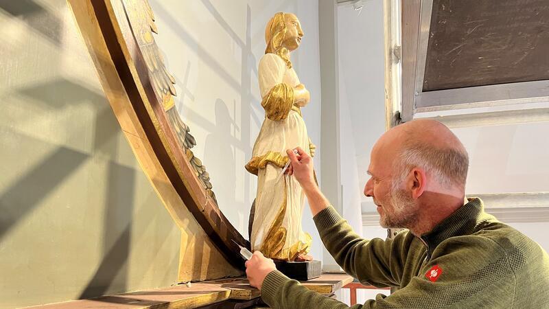 Horneburg: Er holt Jesus aus der Finsternis zurück Gerold Ahrends festigt die Farbe auf einem der beiden Engel des Altars. Die Engel mit Kelch und Kreuz (im Bild) stehen für Liebe und Glauben.