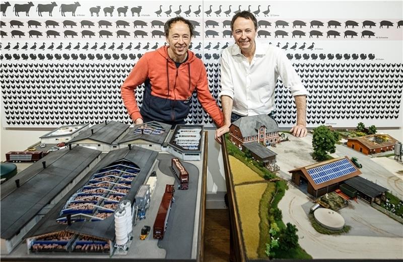 Gerrit (links) und Frederik Braun, Gründer des Miniatur Wunderlands, stehen in ihrer Ausstellung „Sauwohl“ hinter einem Modell der industriellen Schweinemast nach gesetzlichem Mindeststandard (links) und einem Modell der Bio-Schweinemast na