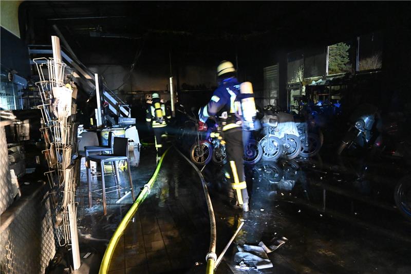 Geschafft: Das Feuer ist aus, Feuerwehrleute suchen in der verrußten Halle eines Motorradhandels in Agathenburg nach letzten Brandnestern. Foto: Vasel