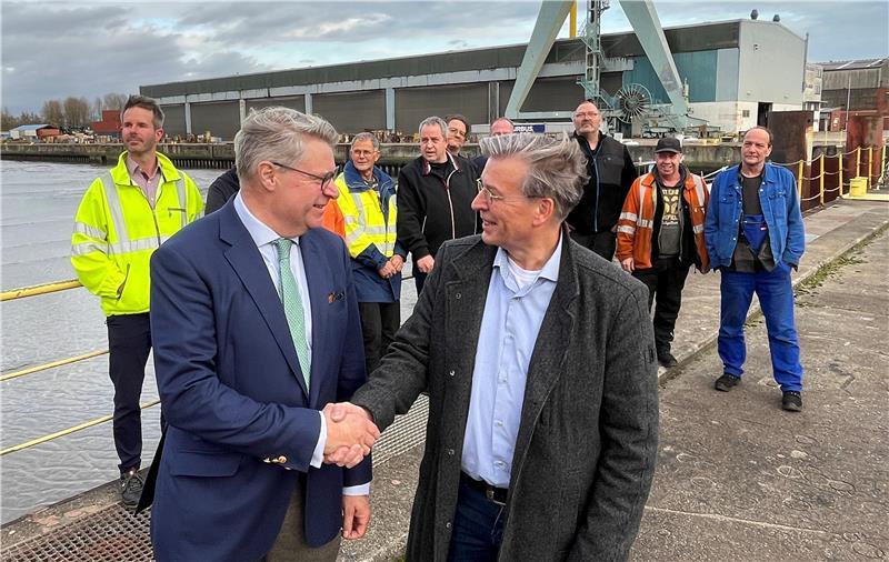 Geschafft: Insolvenzverwalter Dr. Achim Ahrendt gibt dem Betriebsratvorsitzenden der Pella Sietas Werft, Georg Netuschil, die Hand. Im Hintergrund die letzten Beschäftigten der 1635 gegründeten Traditionswerft.