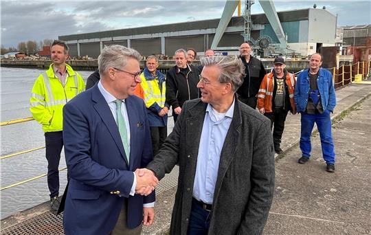 Geschafft: Insolvenzverwalter Dr. Achim Ahrendt gibt dem Betriebsratvorsitzenden der Pella Sietas Werft, Georg Netuschil, die Hand. Im Hintergrund die letzten Beschäftigten der 1635 gegründeten Traditionswerft.
