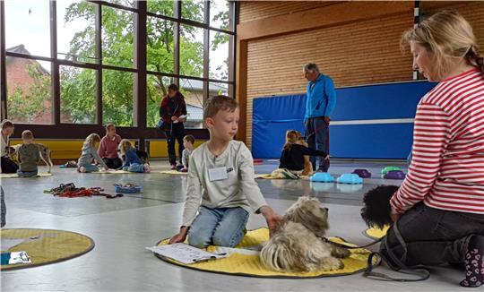Gespannt warten Zwei- und Vierbeiner in der Turnhalle in Mulsum auf den Beginn der Prüfung, darunter auch Luca, die Fellnasen Hanno und Filou und Yvonne Heins.