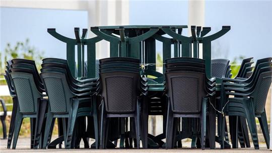 Gestapelte Tische und Stühle für die Außengastronomie stehen auf dem Platz an der Seebrücke.