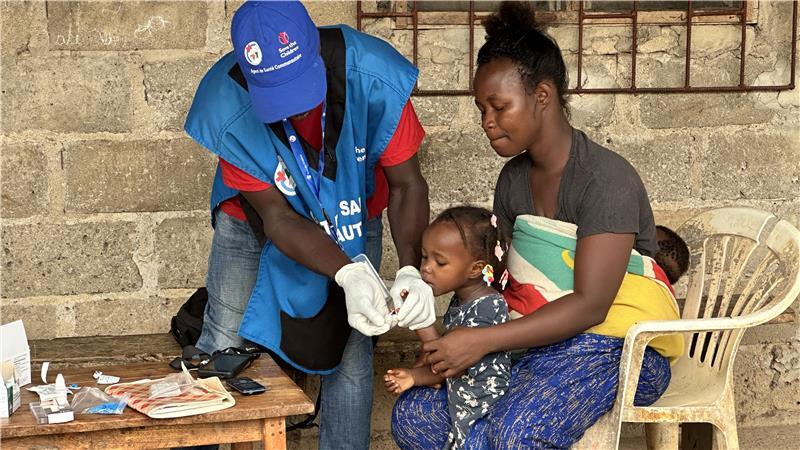 Gesundheitshelfer Michel Bayoro untersucht ein kleines Mädchen im Dorf Tiépa auf Malaria-Symptome.