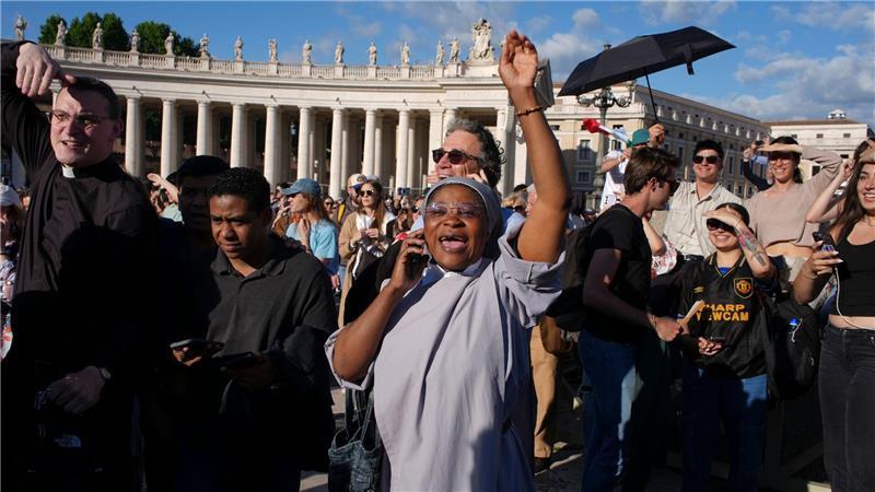 Gläubige telefonieren mit ihren Angehörigen, um vom neuen Papst zu berichten.