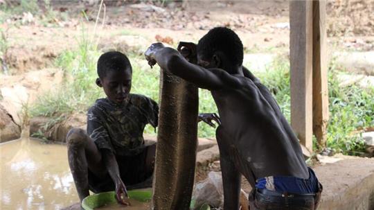 Goldverarbeitungsanlage in der Region Brong-Ahafo in Ghana: Zwei kleine Jungen waschen das Erz, um es vom Schlamm zu trennen.