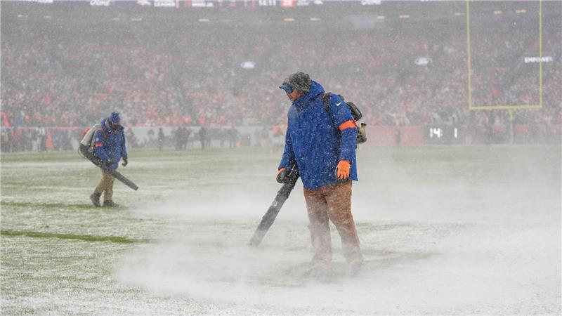 Greenkeeper der Denver Broncos blasen den Schnee von den Yard-Linien.