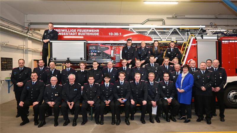 Buxtehude will hier schon 2027 ein neues Feuerwehrhaus bauen Gruppenfoto mit den Geehrten und Beförderten an der Drehleiter.