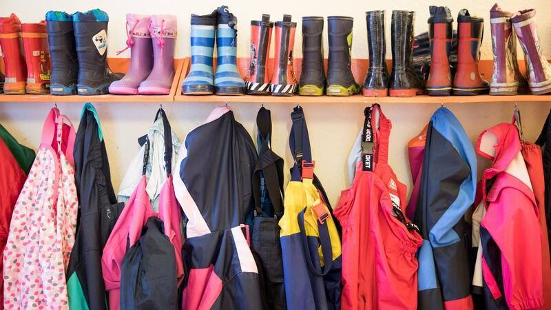Land plant Perspektiv-Kitas in Problemvierteln Gummistiefel und Regenhosen von Kindern hängen in einer Kita in Wedel an einem Regal.