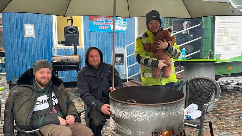 Stader Protest-Camp der Landwirte: Im strömenden Regen an der Feuertonne Jan Christoph Wandt, Christian Wandt und Sina Bernhard mit Baby sitzen am 26. Januar 2024 im Protestcamp der Landwirte an einer Feuertonne auf dem Platz Am Sande.