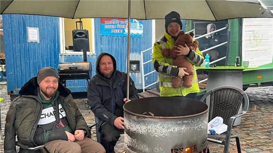 Jan Christoph Wandt, Christian Wandt und Sina Bernhard mit Baby sitzen am 26. Januar 2024 im Protestcamp der Landwirte an einer Feuertonne auf dem Platz Am Sande.