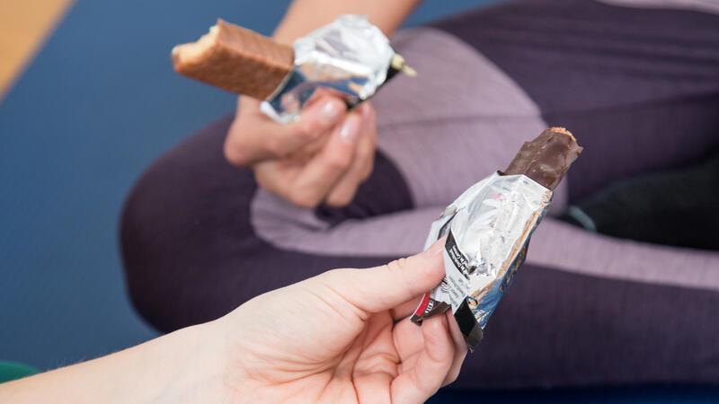 Zwei Sportler halten Protein-Riegel in der Hand.